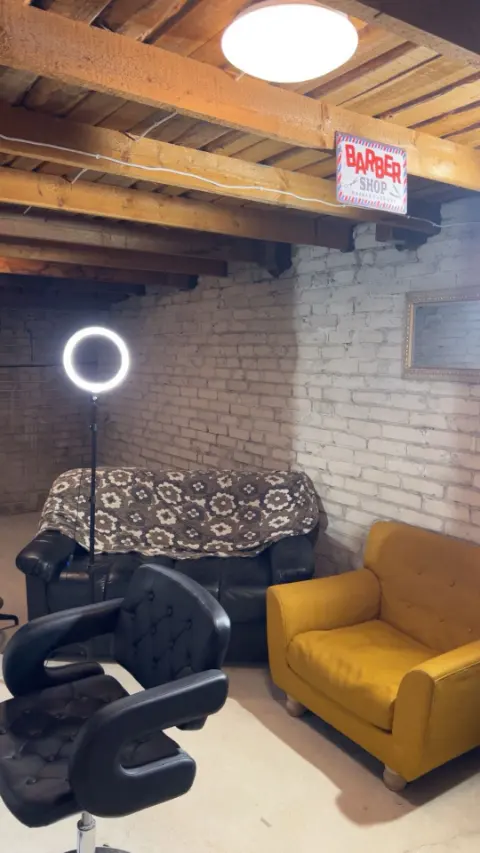 Ootenurk: diivan, kollane tugitool ja silt Barber Shop.